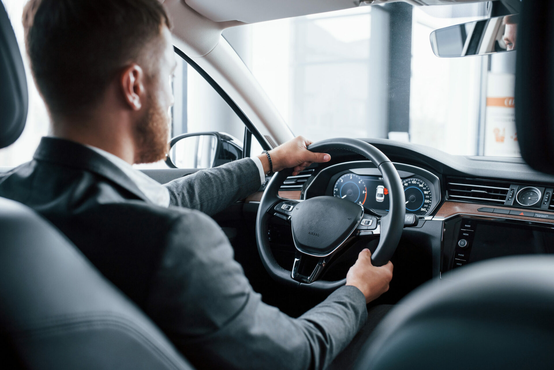 Modern businessman trying his new car in the automobile salon.